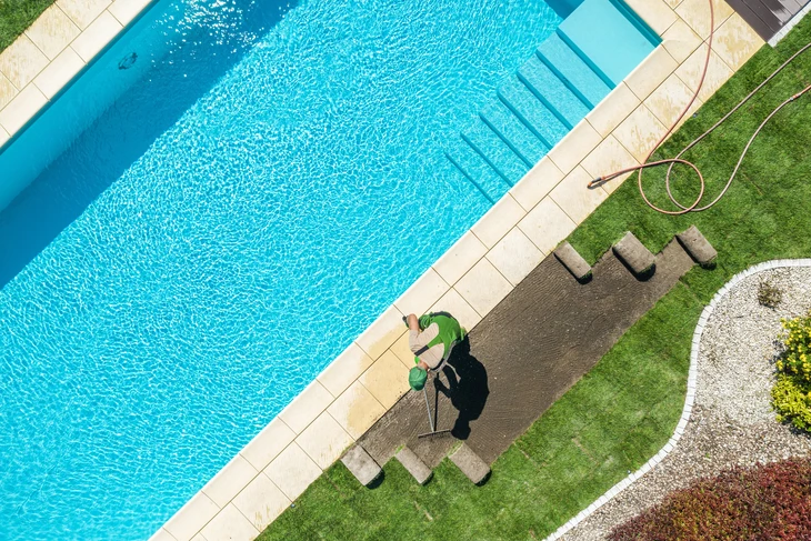 Terrasse extérieure privée avec piscine rectangulaire encastrée, deux transats blancs avec coussins beiges sur platelage bois