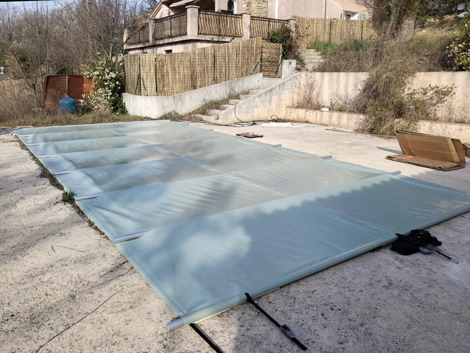 Extérieur résidentiel avec piscine couverte par une bâche de sécurité bleue tendue