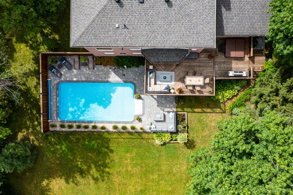 "Vue aérienne d'une piscine arrière-cour sereine, eaux vierges embrassées par une végétation luxuriante