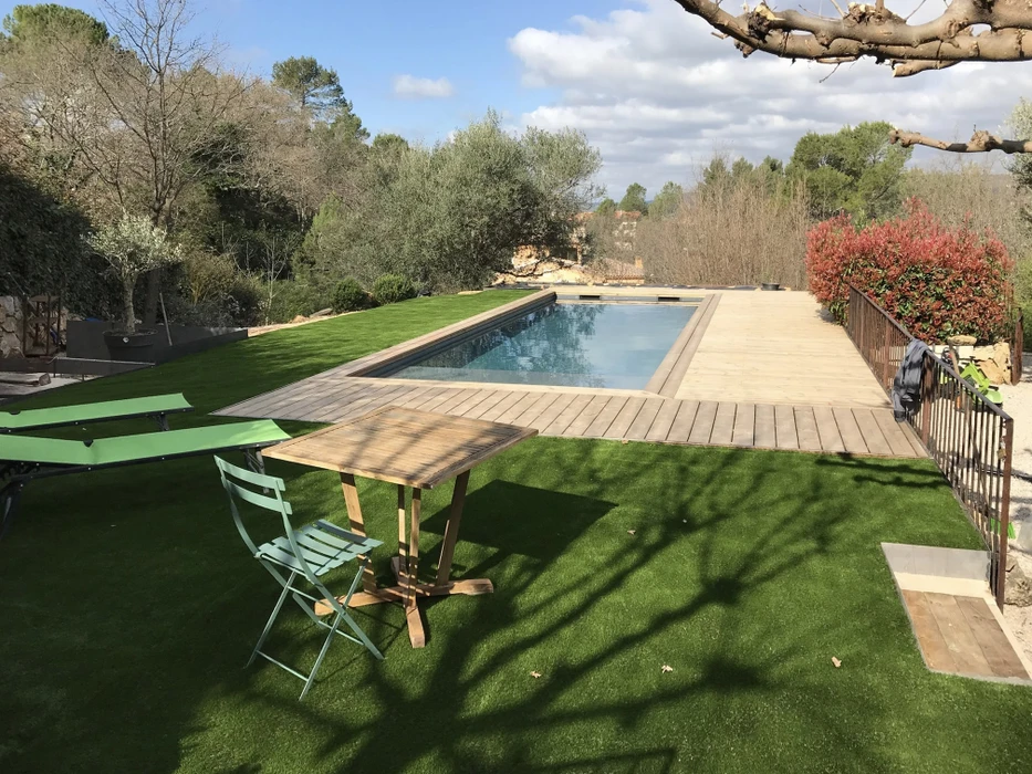 Piscine extérieure rectangulaire avec couverture automatique à enrouleur, située dans jardin paysagé avec montagnes boisées en arrière-plan