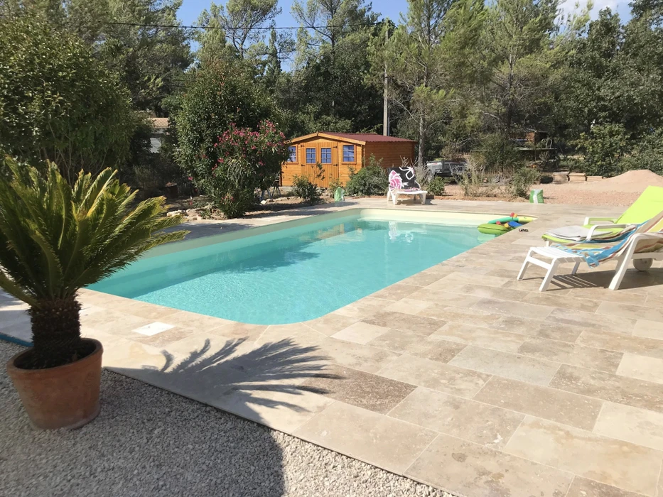 Piscine rectangulaire extérieure avec escalier d'angle en béton, située dans jardin avec pelouse artificielle
